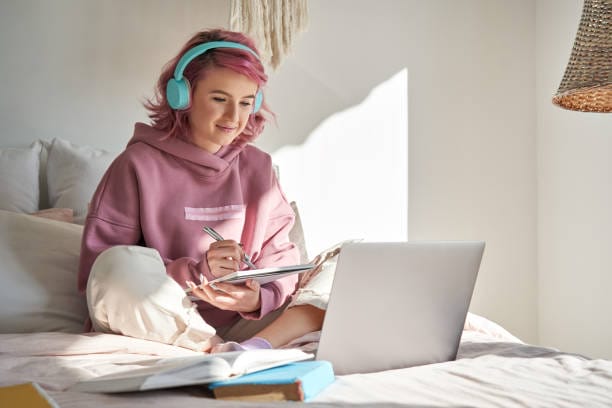 стокові фото, фото роялті-фрі та зображення на тему хіпстер студентка-підліток з рожевим волоссям дивитися онлайн вебінар навчання в ліжку. - remote learning college